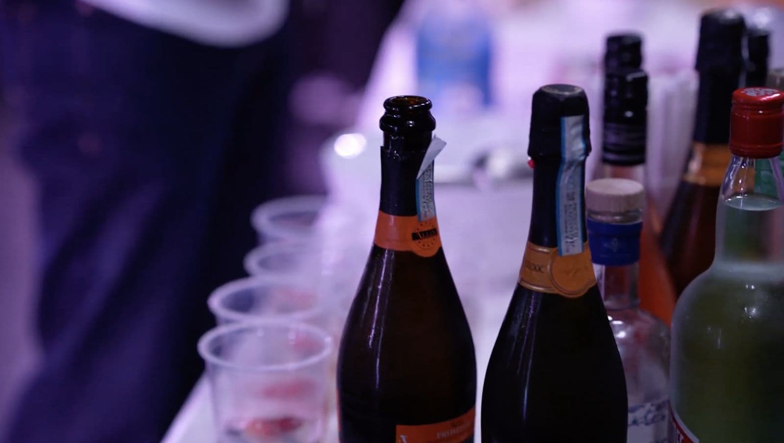 Bottles of prosecco lined up beside rows of glasses ready for arrival drinks