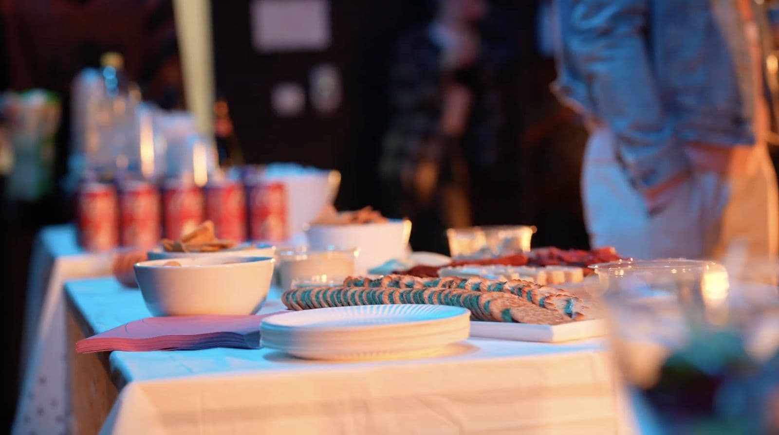 A party table laid with festive food, soft drinks and stacked plates