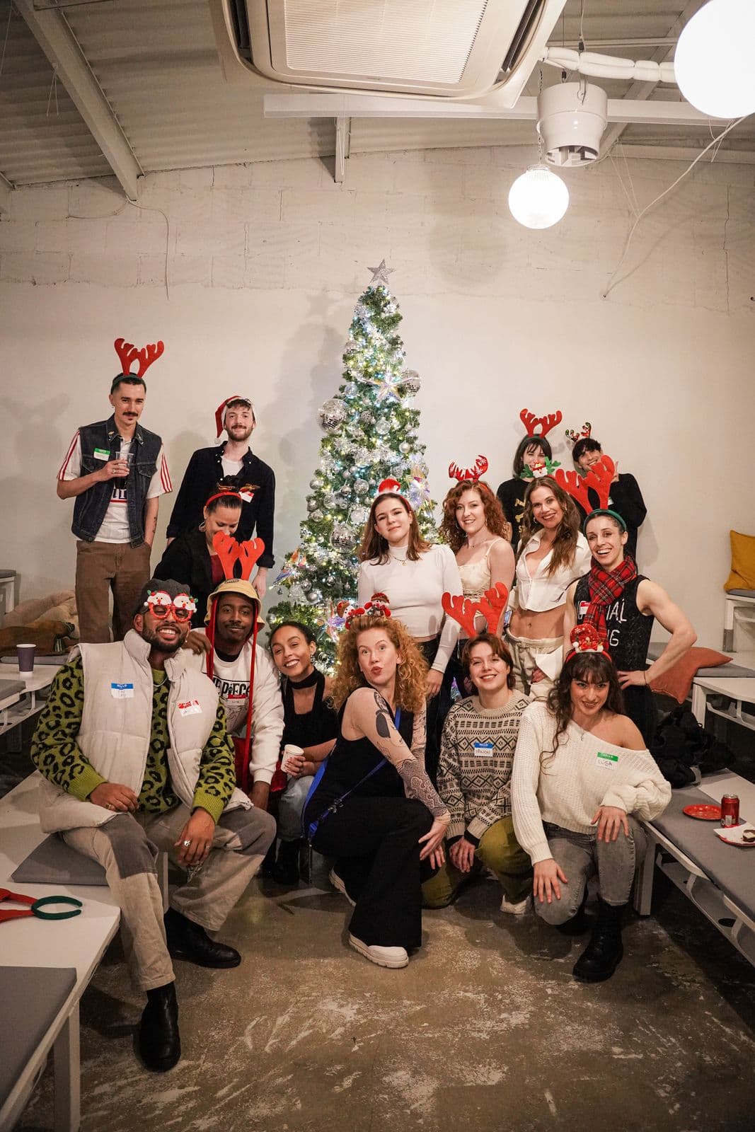 A Christmas party group in antlers posing in front of a silver and white Christmas tree