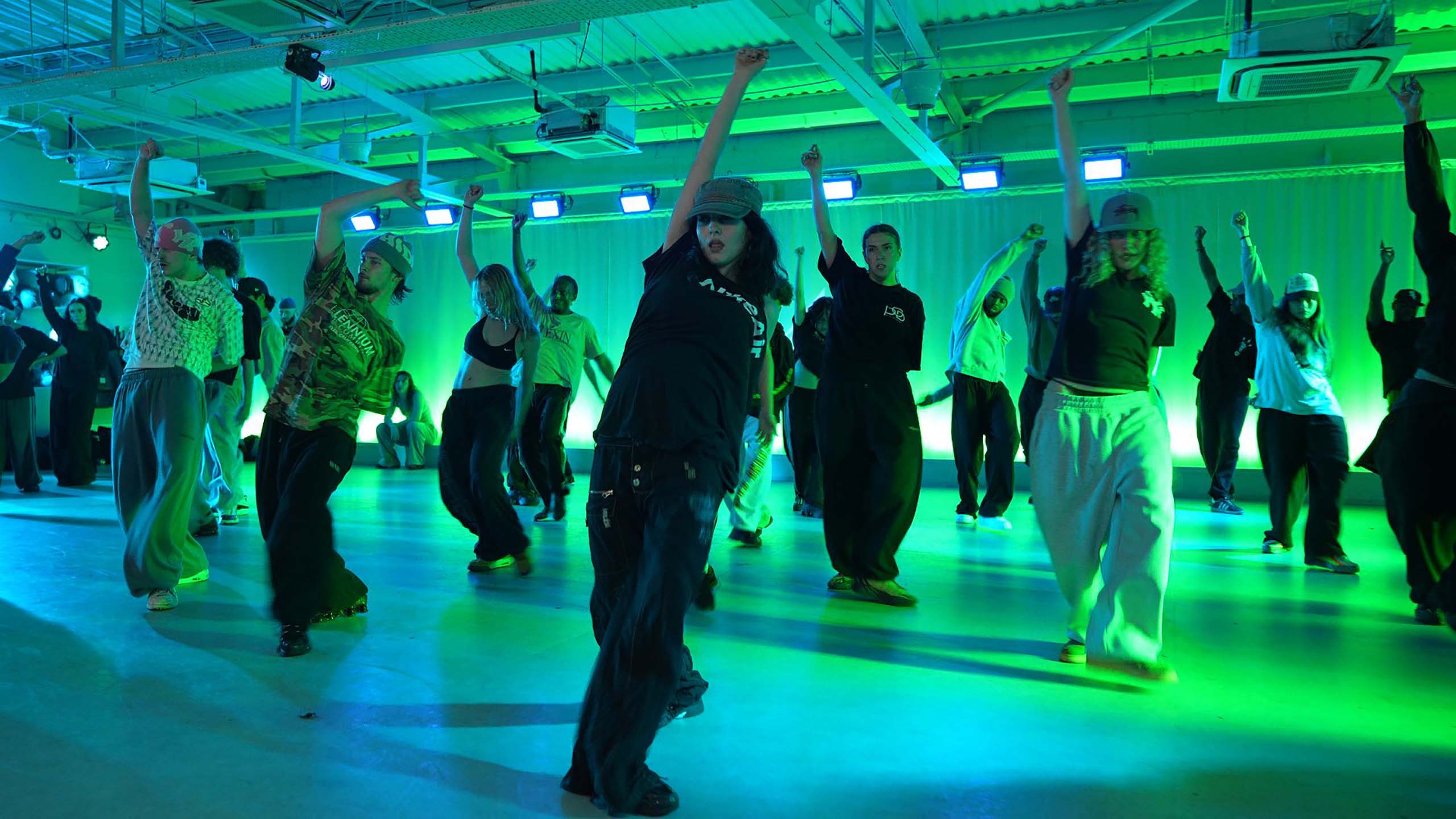 Dancers mid-class in a green-lit Manor studio
